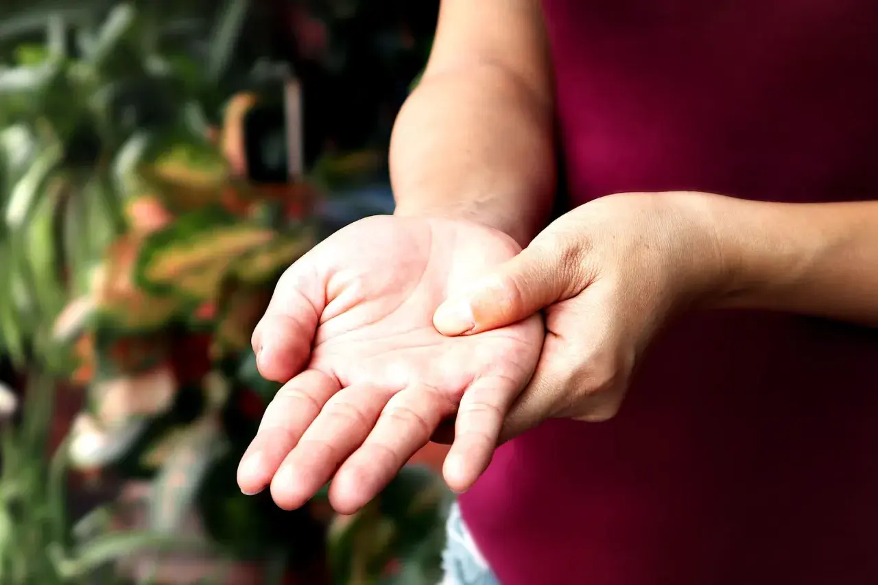 Mano che si tocca il polso, forse per un sintomo di polineuropatia.