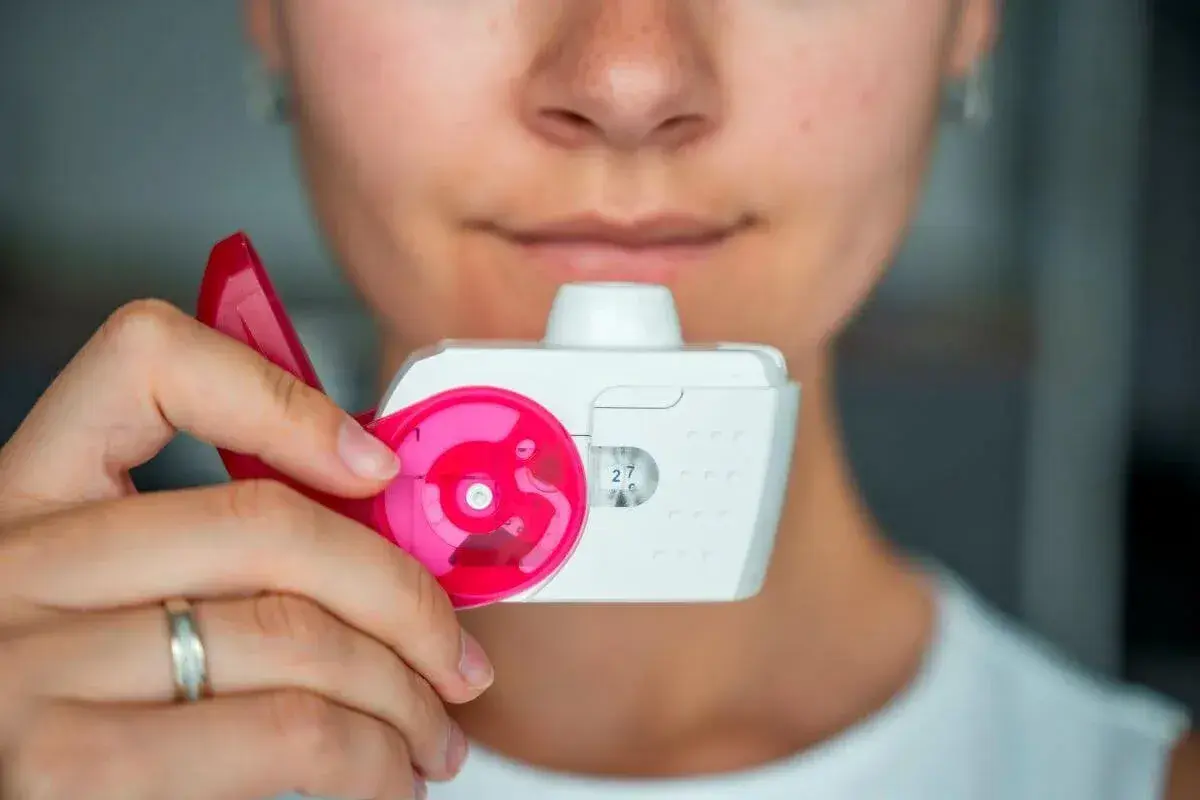 Eine Person hält einen Inhalator, bereit zum Inhalieren.