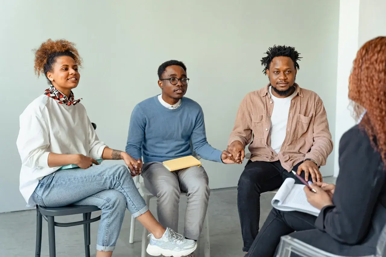 Grupo de personas en círculo, tomándose de las manos, fortaleciendo sus relaciones de amistad y apoyo mutuo.
