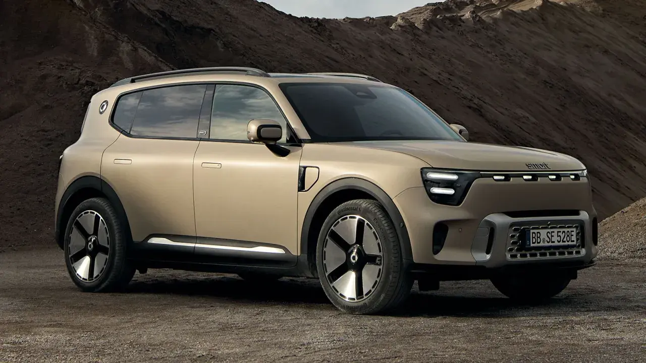 En smart 5-dörrars SUV i sandfärgad metallic står på en grusväg. Bilen har en modern design med LED-lampor och unika fälgar.