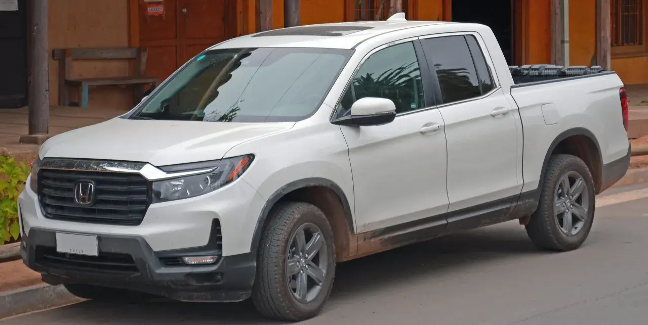 Biały Honda Ridgeline z błotem na progach, gotowy na przygodę.