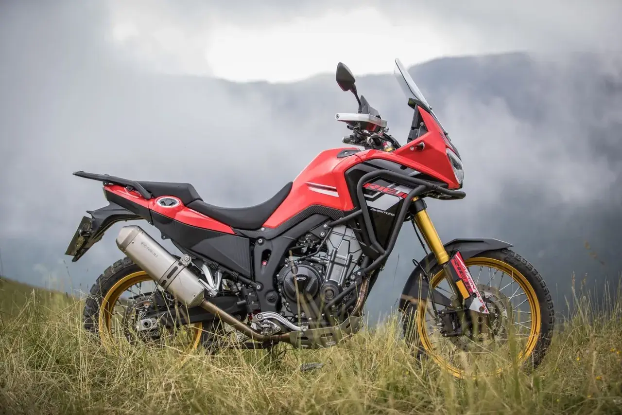 Rieju Aventura 500, lista para la aventura. Ficha técnica de esta moto trail roja y negra en un paisaje montañoso.