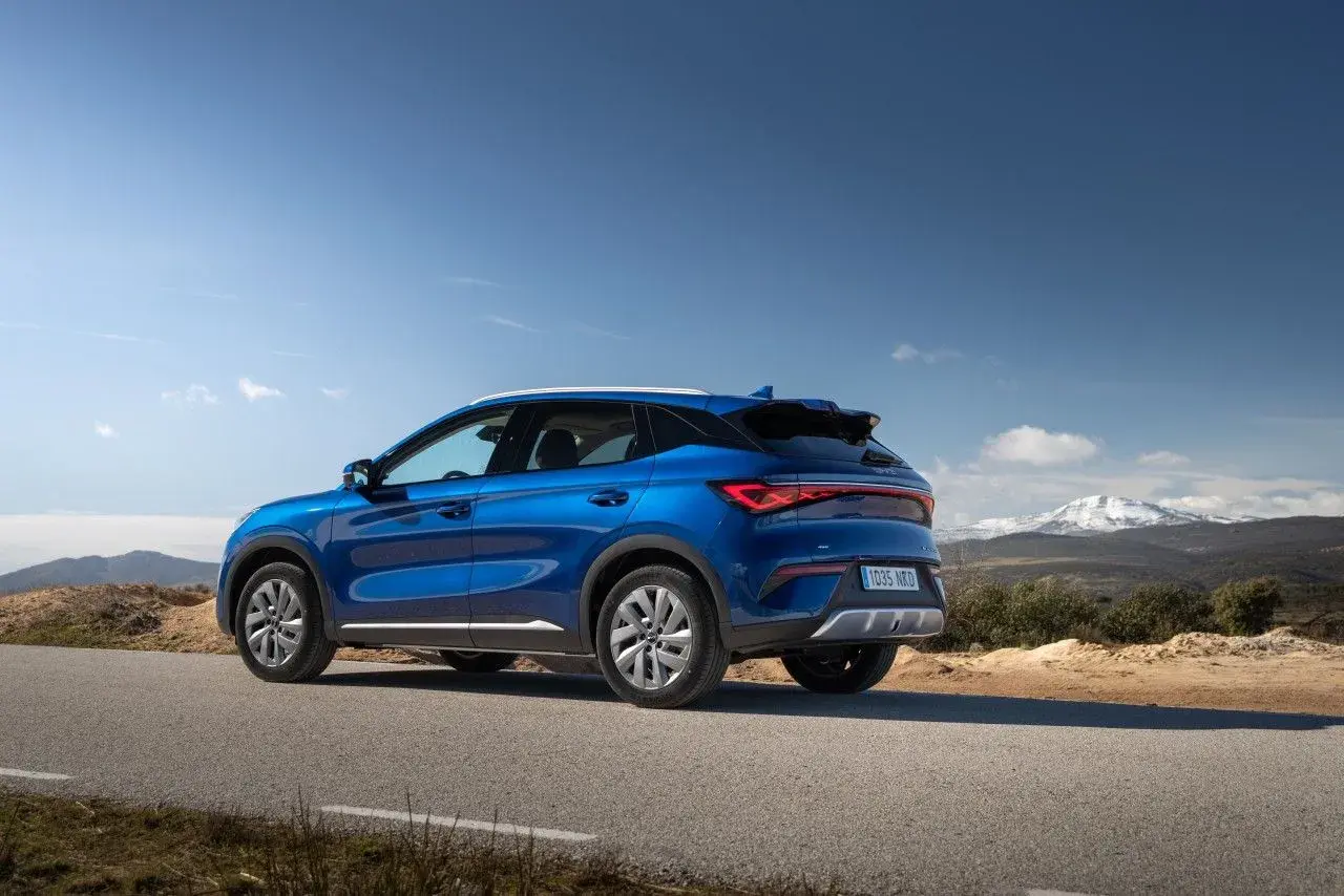 Un BYD Atto 3 azul en una carretera rural, listo para una prueba de manejo con montañas nevadas al fondo.