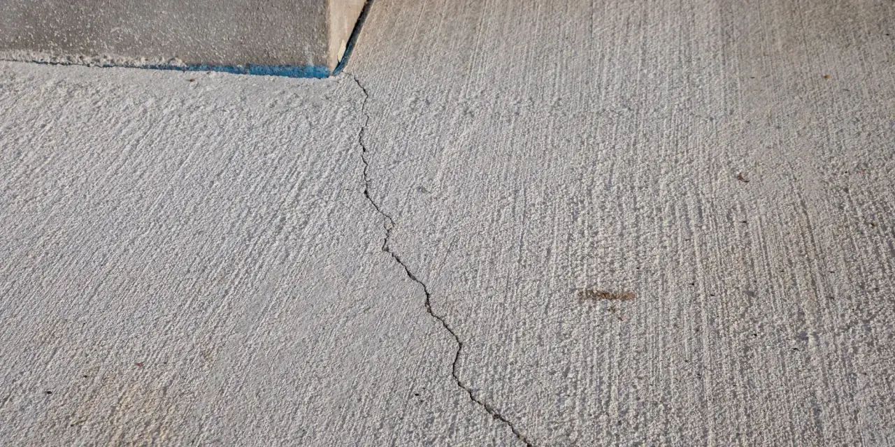Une fissure traverse une dalle béton fraîchement coulée, témoignant des défis pour faire une dalle béton parfaite.