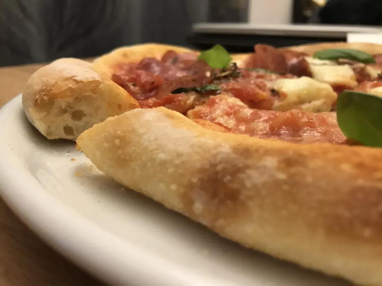 Nahaufnahme einer köstlichen Pizza mit dickem, luftigem Rand, belegt mit Tomaten, Käse und Salami. Ein echter Genuss, wie ein kleiner "pizza canotto".