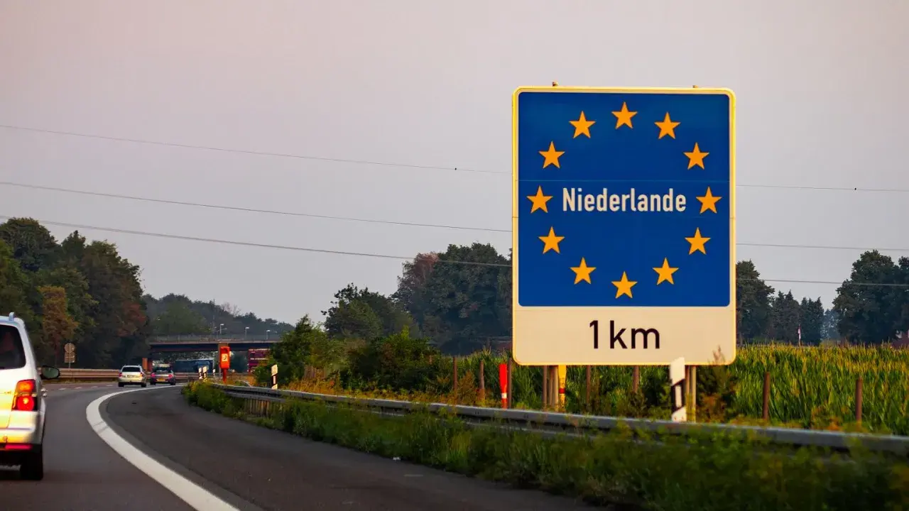 Granica z Holandią, winieta nl. Znak informuje o zbliżaniu się do Holandii, 1 km.