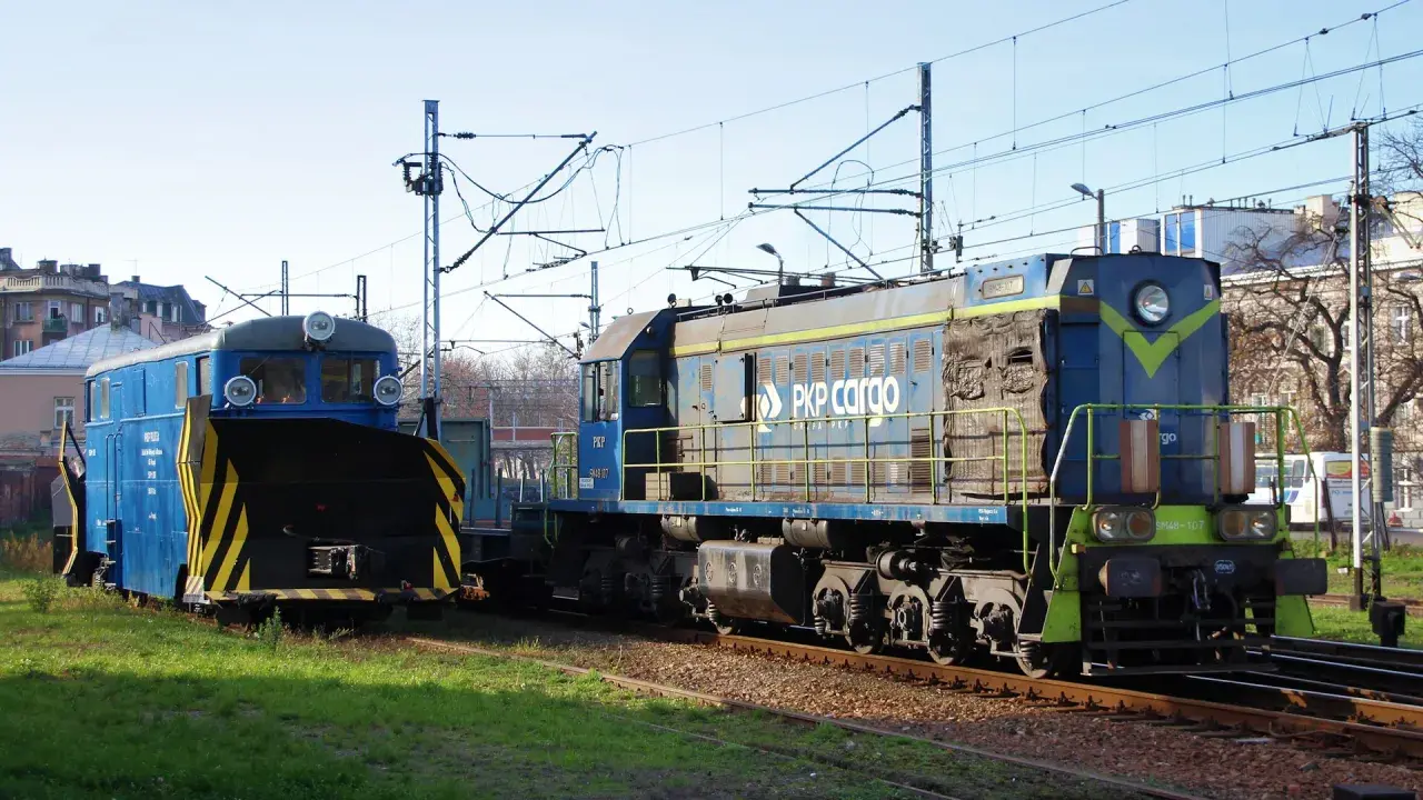 Dwie lokomotywy PKP Cargo, w tym jedna z pługiem śnieżnym, stoją na torach. Lokomotywa tem2 jest niebieska z żółtymi pasami.
