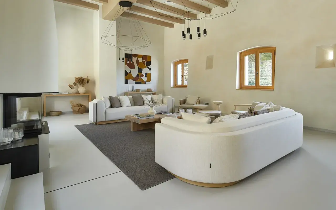 Salón moderno con sofás blancos, chimenea y suelo de microcemento sobre azulejos.