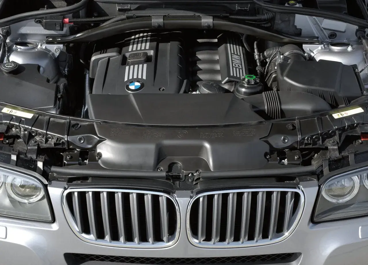 Silnik BMW X3 2005. Widok komory silnika z charakterystyczną atrapą chłodnicy i logo BMW.