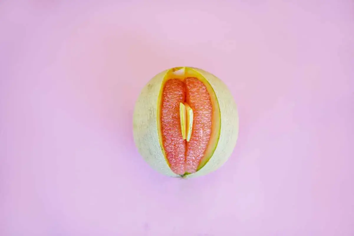 En melon skuren på mitten, med saftigt rött fruktkött som påminner om ett svullet underliv gravid.