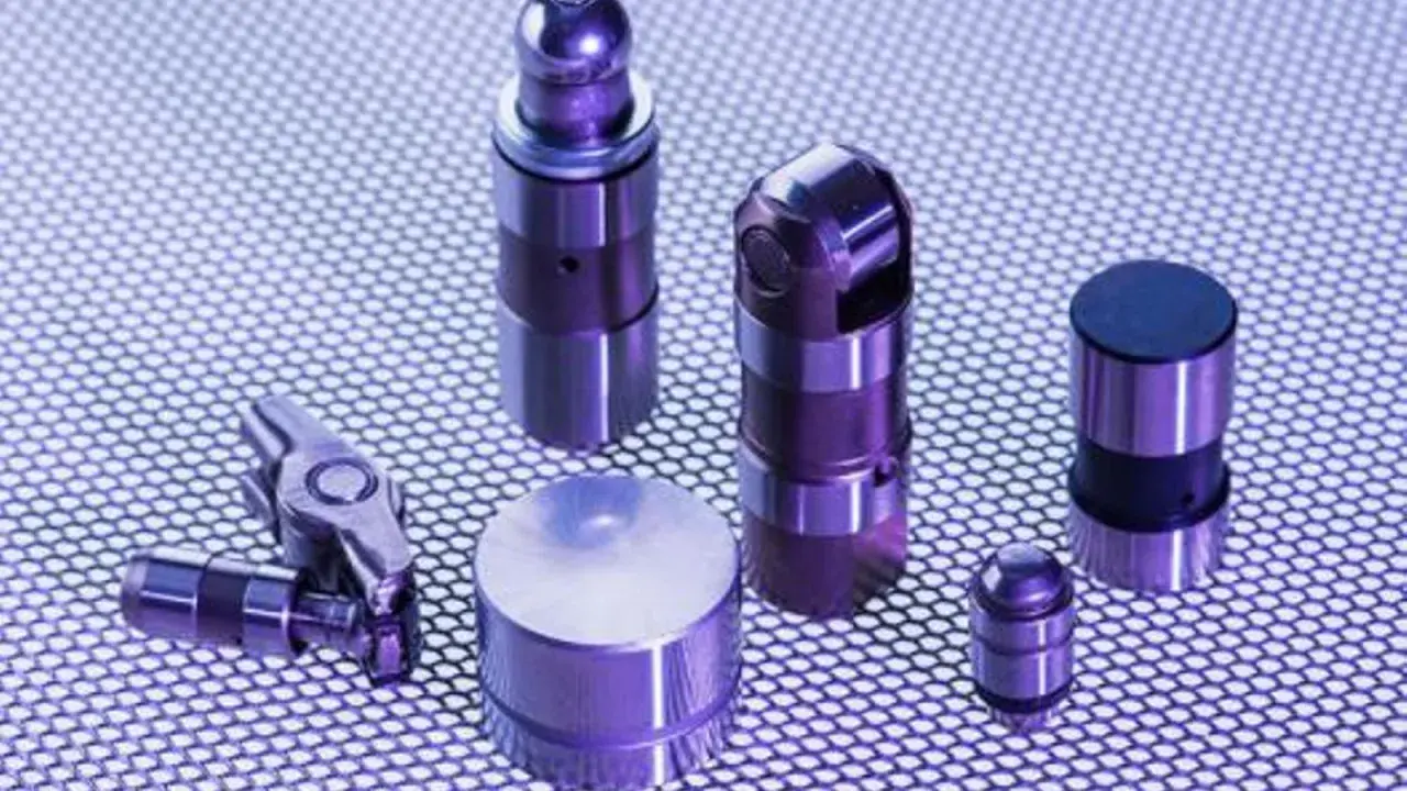 Varios taques hidráulicos de metal, algunos con forma cilíndrica y otros con un diseño más complejo, dispuestos sobre una superficie texturizada.