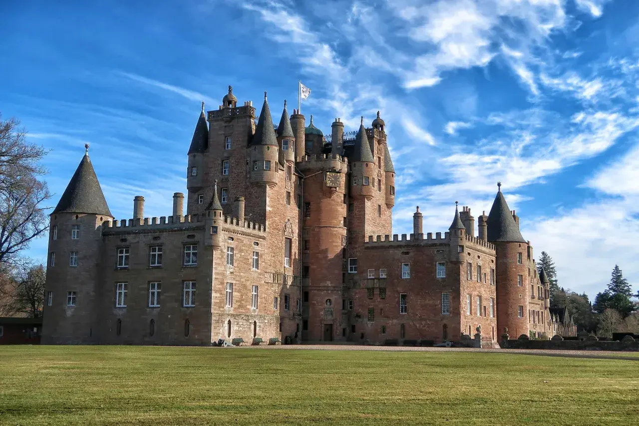 Castillo escocés con torres cónicas y un gran césped verde, perfecto para tus viajes a Escocia.