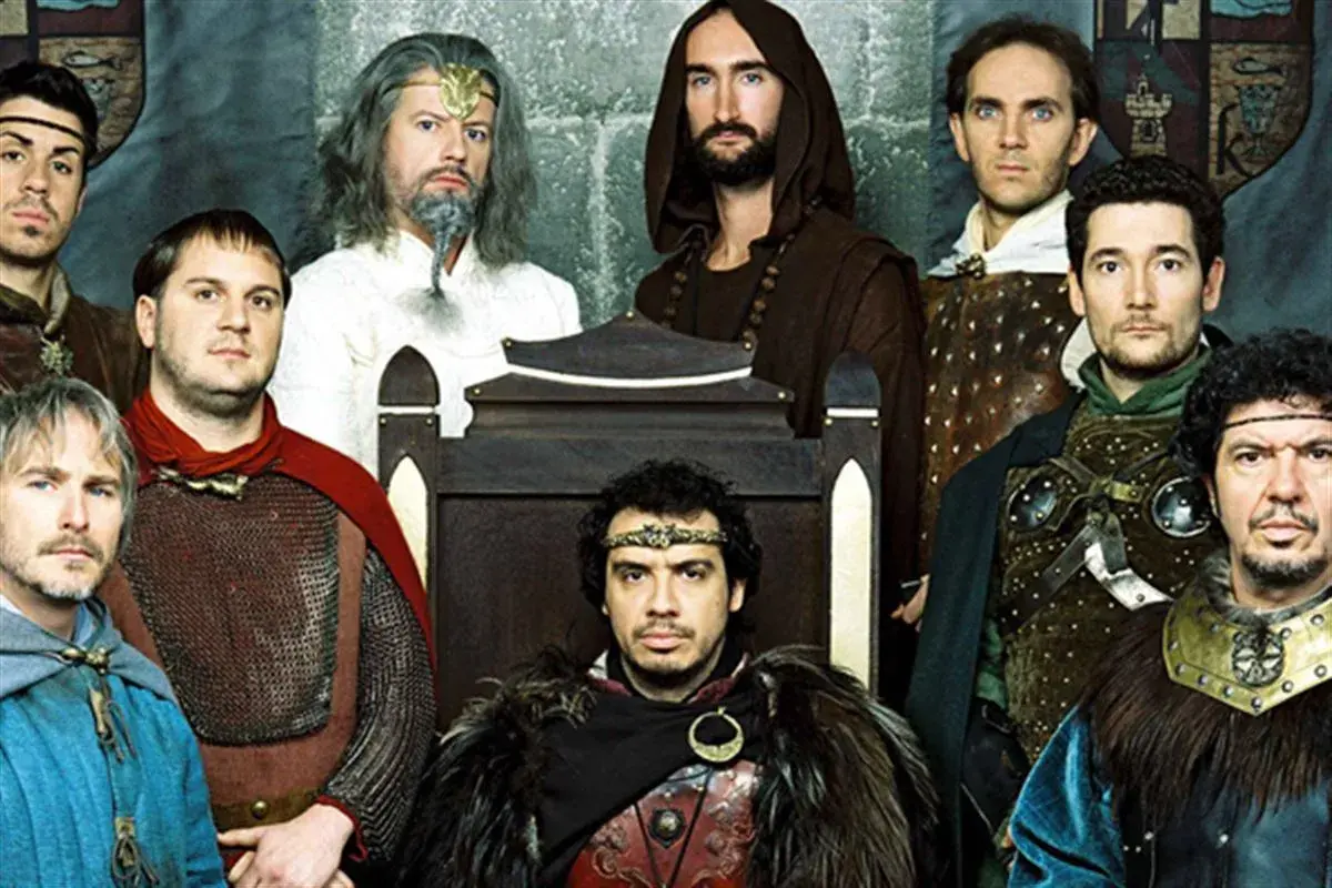 Le casting de Kaamelott réuni, des chevaliers aux allures diverses, certains sur un trône, d'autres en armure.