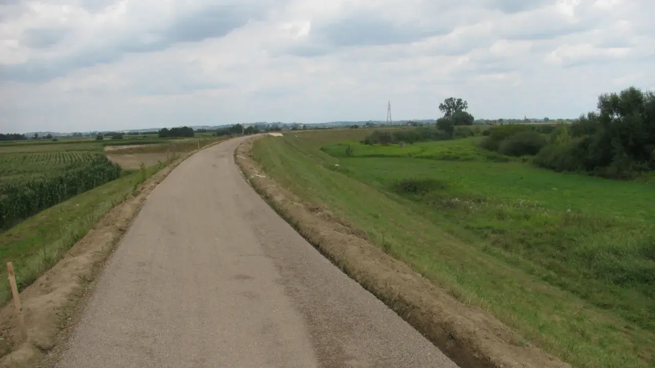 Asfaltowa ścieżka rowerowa velo raba wije się wśród pól kukurydzy i zielonych łąk, zapraszając na przejażdżkę.