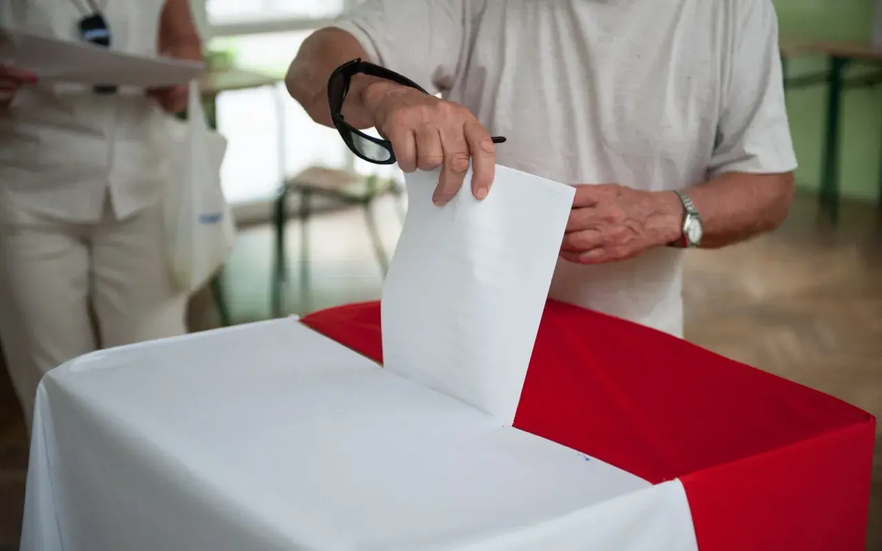 Mężczyzna wrzuca kartę do głosowania do urny. To ważny moment, nawet jeśli są to wybory poza miejscem zamieszkania.