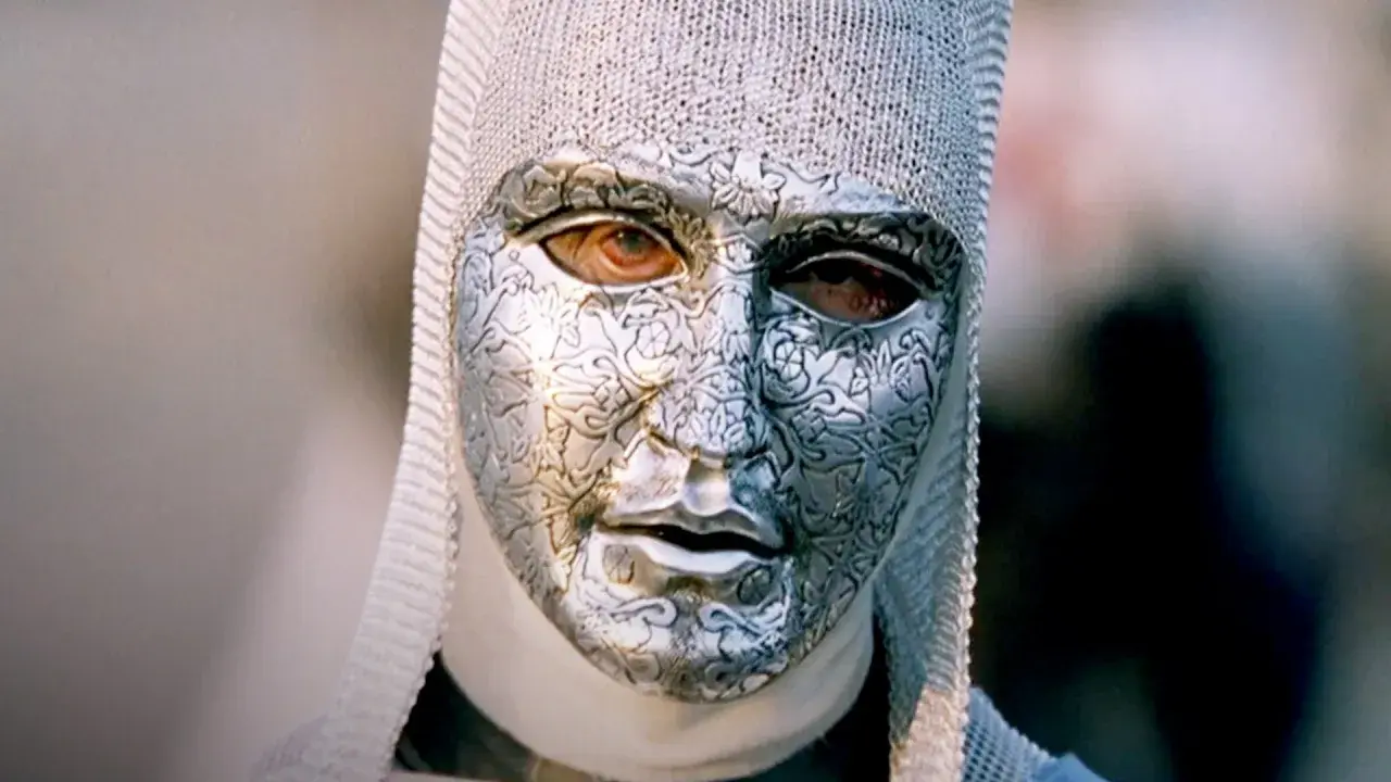 En mystisk figur med en detaljerad silvermask och kedjehätta, en karaktär från rollistan i Kingdom of Heaven.