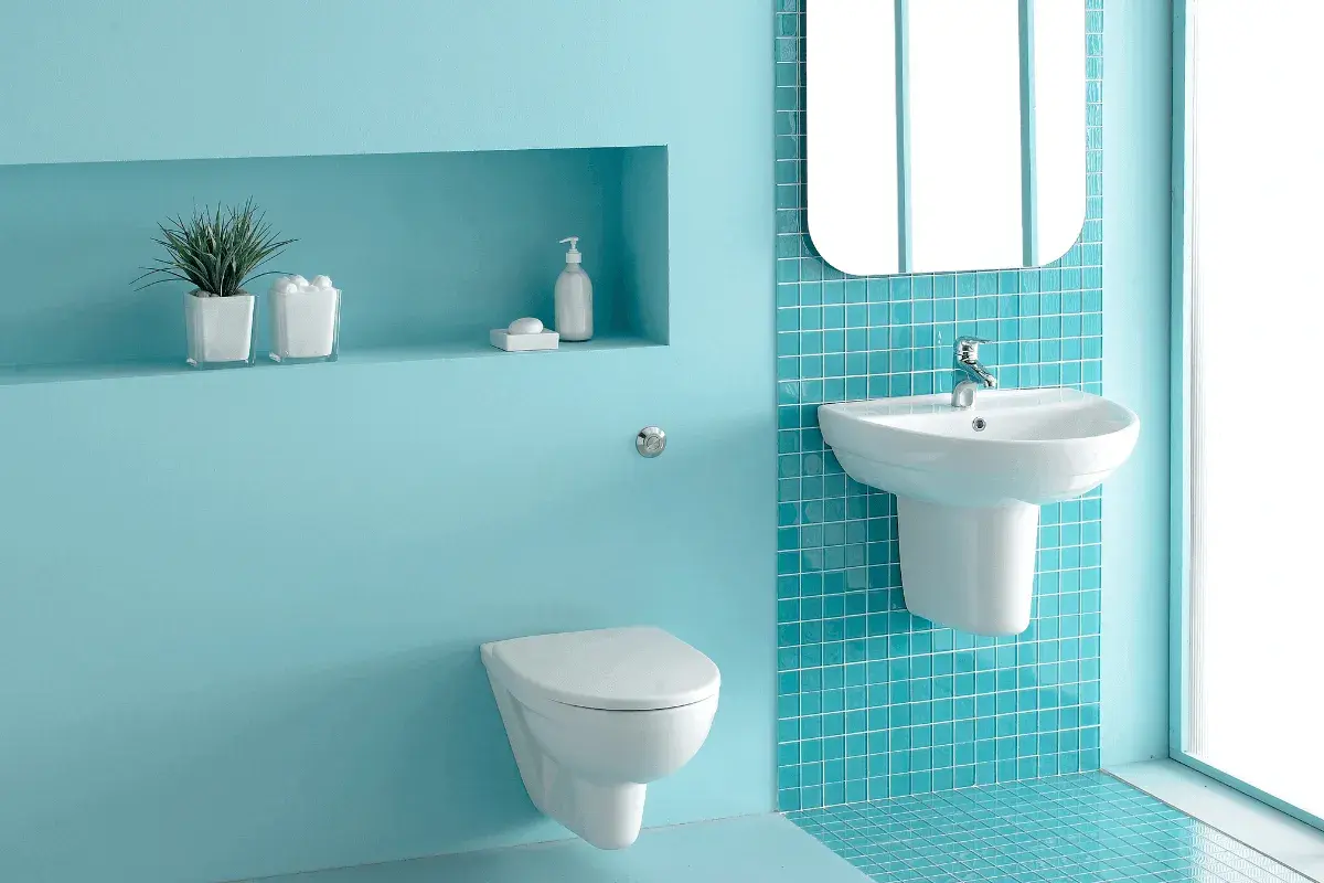 Un moderno bagno verde acqua e bianco con sanitari sospesi, lavabo e specchio.