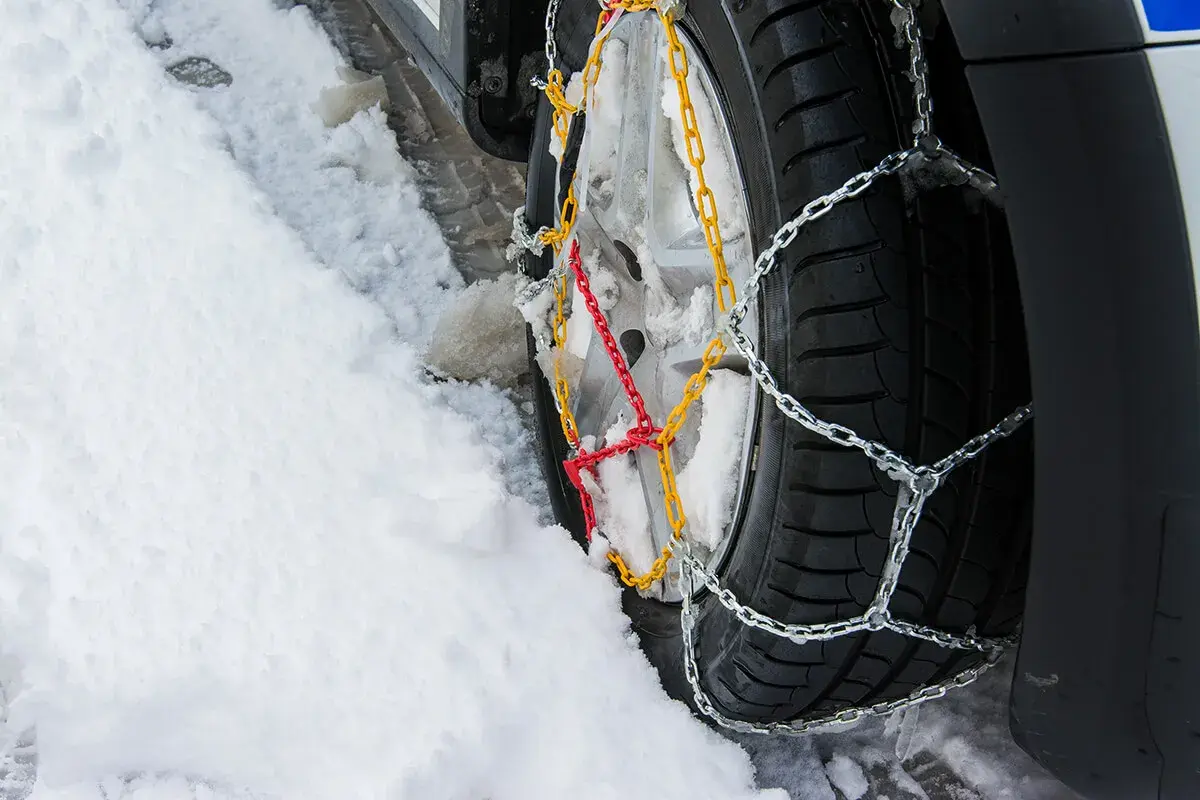 Łańcuchy na kołach 4x4 poprawiają przyczepność na śniegu. Widać je na oponie w zaspie.