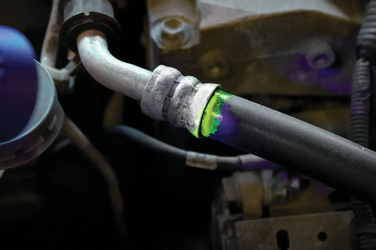 Detectando una fuga de aire en el sistema de aire acondicionado con tinte fluorescente verde y luz ultravioleta.