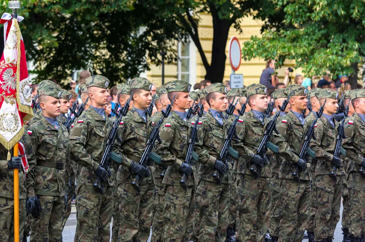 Żołnierze w mundurach polowych, z karabinami, maszerują w defiladzie. To widok z kategorii e wojsko, symbol dumy narodowej.