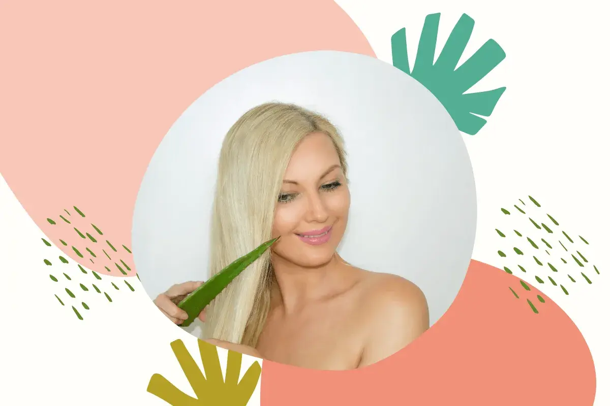 Blondynka z uśmiechem dotyka włosów liściem aloesu, który może być naturalnym żelem aloesowym na włosy.
