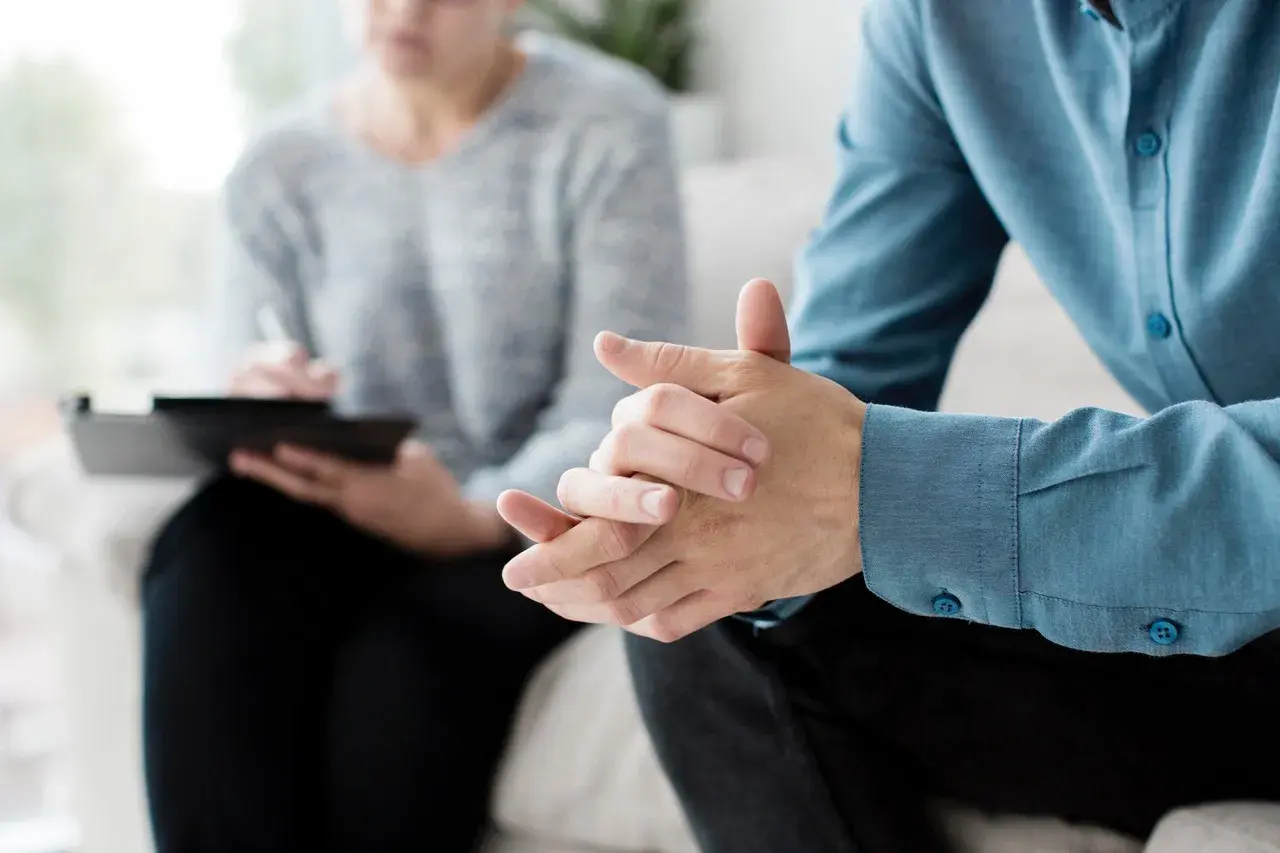 Due mani intrecciate in un colloquio, forse per affrontare la ruminazione mentale e valutare l'uso di farmaci.