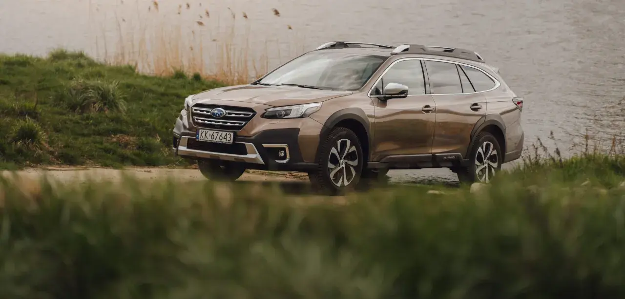 Brązowy Subaru Outback 2025 zaparkowany nad jeziorem, gotowy na przygodę.