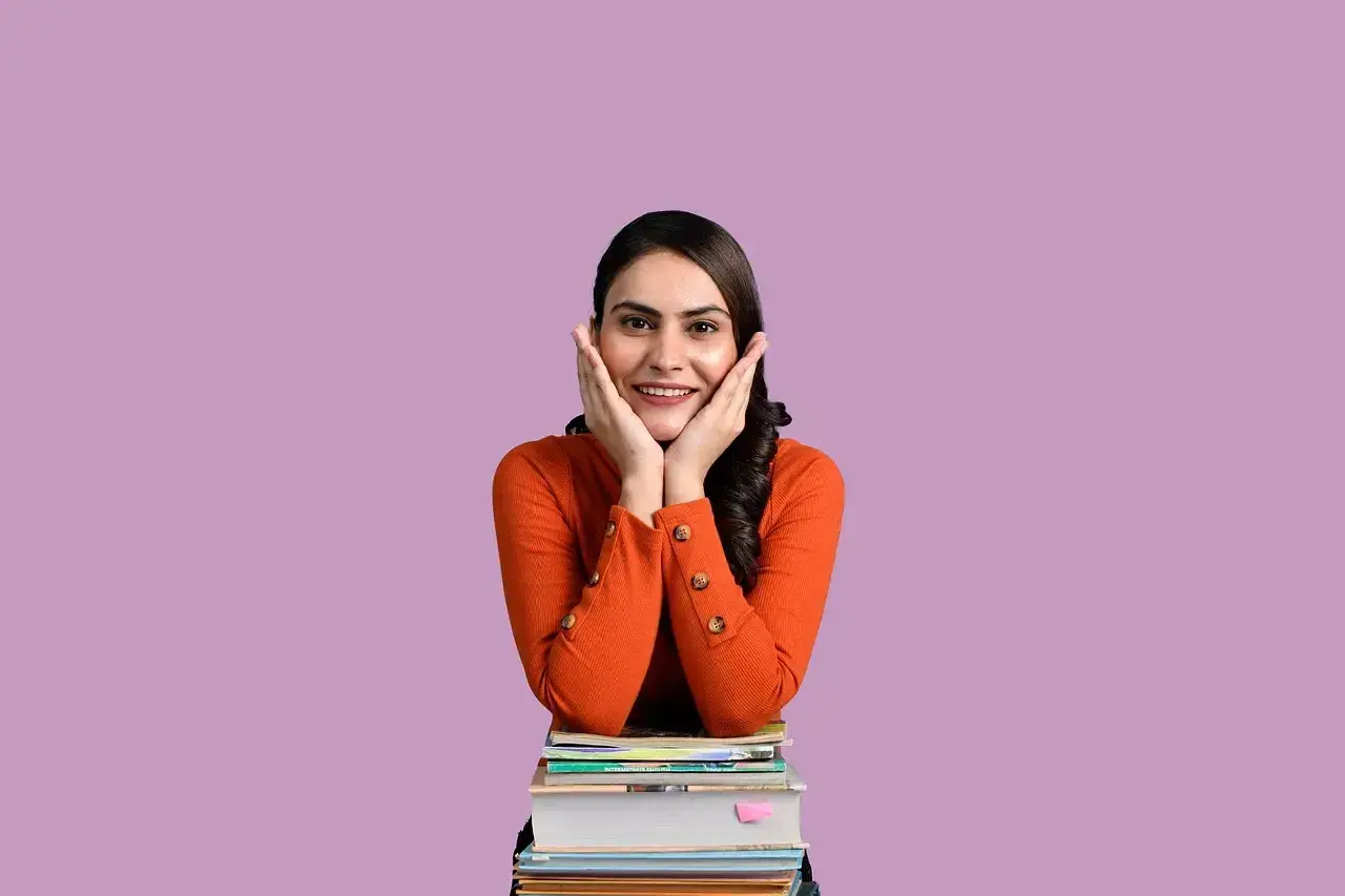 Ragazza sorridente con le mani sulle guance, appoggiata a una pila di libri. "Wow!" esclamazioni in inglese.