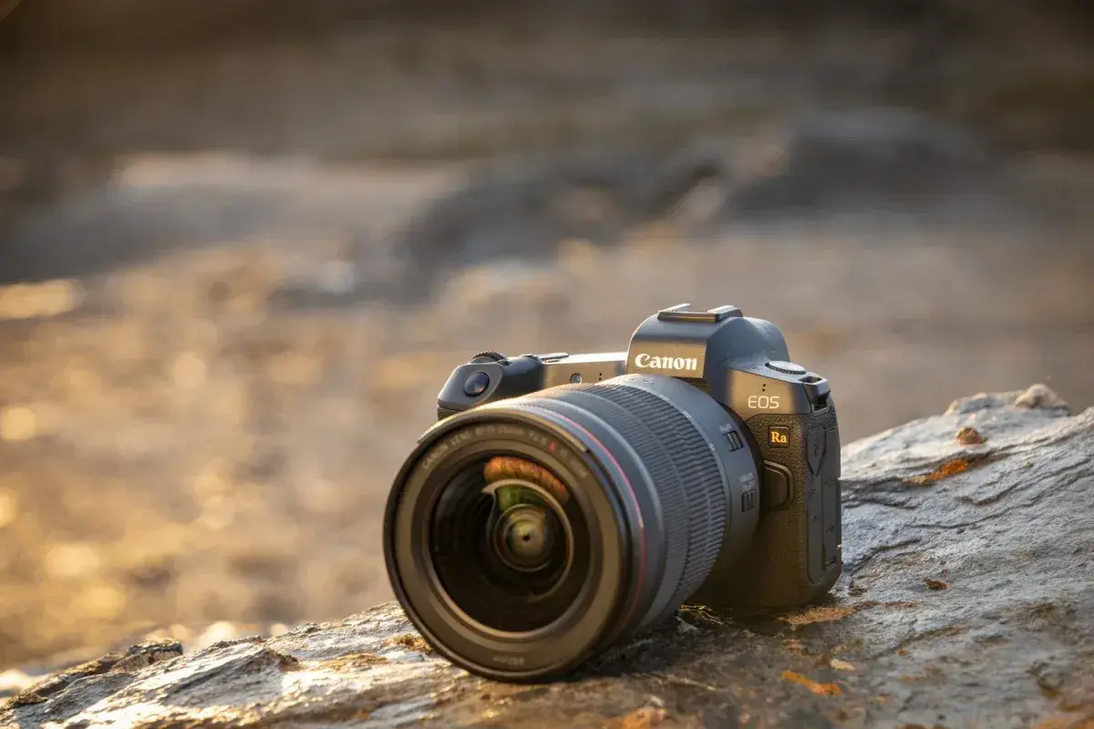 Profesjonalny aparat do astrofotografii Canon EOS Ra z obiektywem RF 15-35mm f/2.8 L IS USM leży na kamieniu.