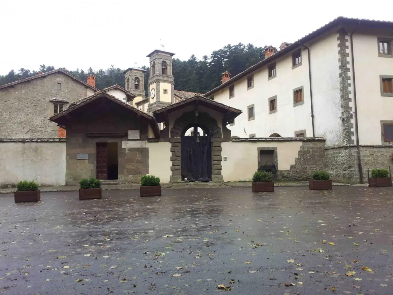 Cortile umido con foglie cadute davanti all'ingresso di Camaldoli, dove si trova questo antico eremo.