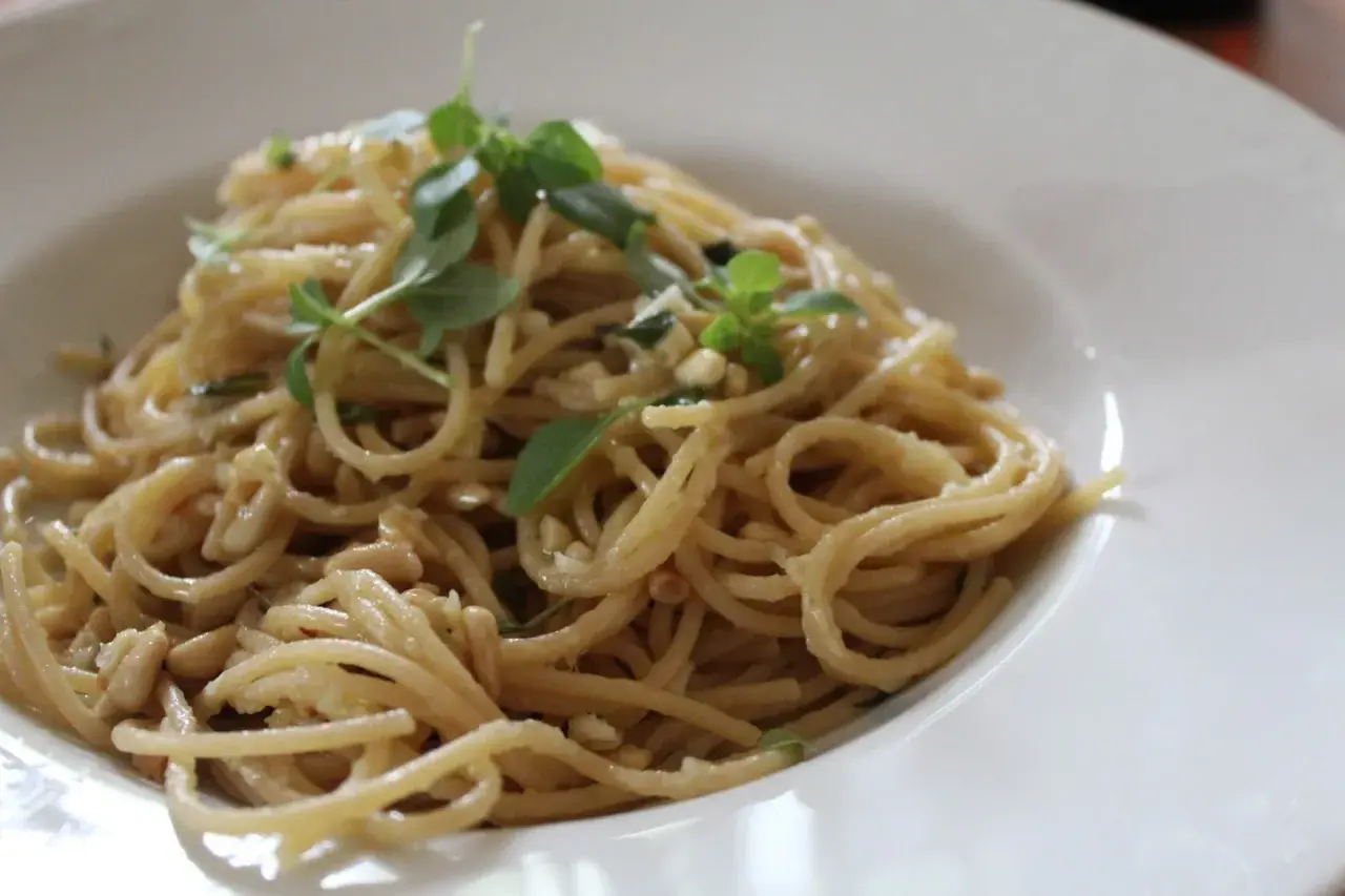 Deliciosa pasta con piñones y hierbas frescas, servida en un plato blanco.