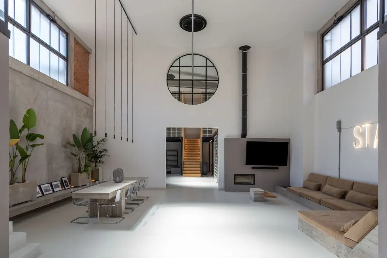 Geräumiger **Industrie-Loft** mit Betonwänden, großem Esstisch, Kamin und gemütlicher Sitzecke.