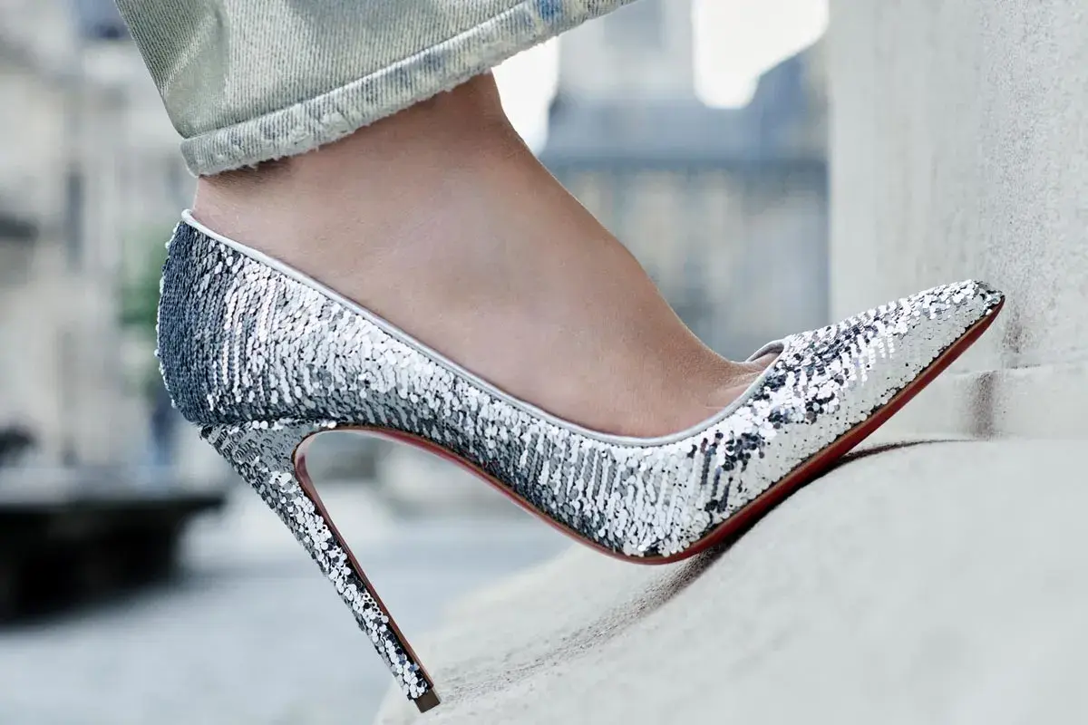 Une tenue jean avec talon, des escarpins argentés à paillettes brillent sous la lumière, prêts pour une soirée glamour.