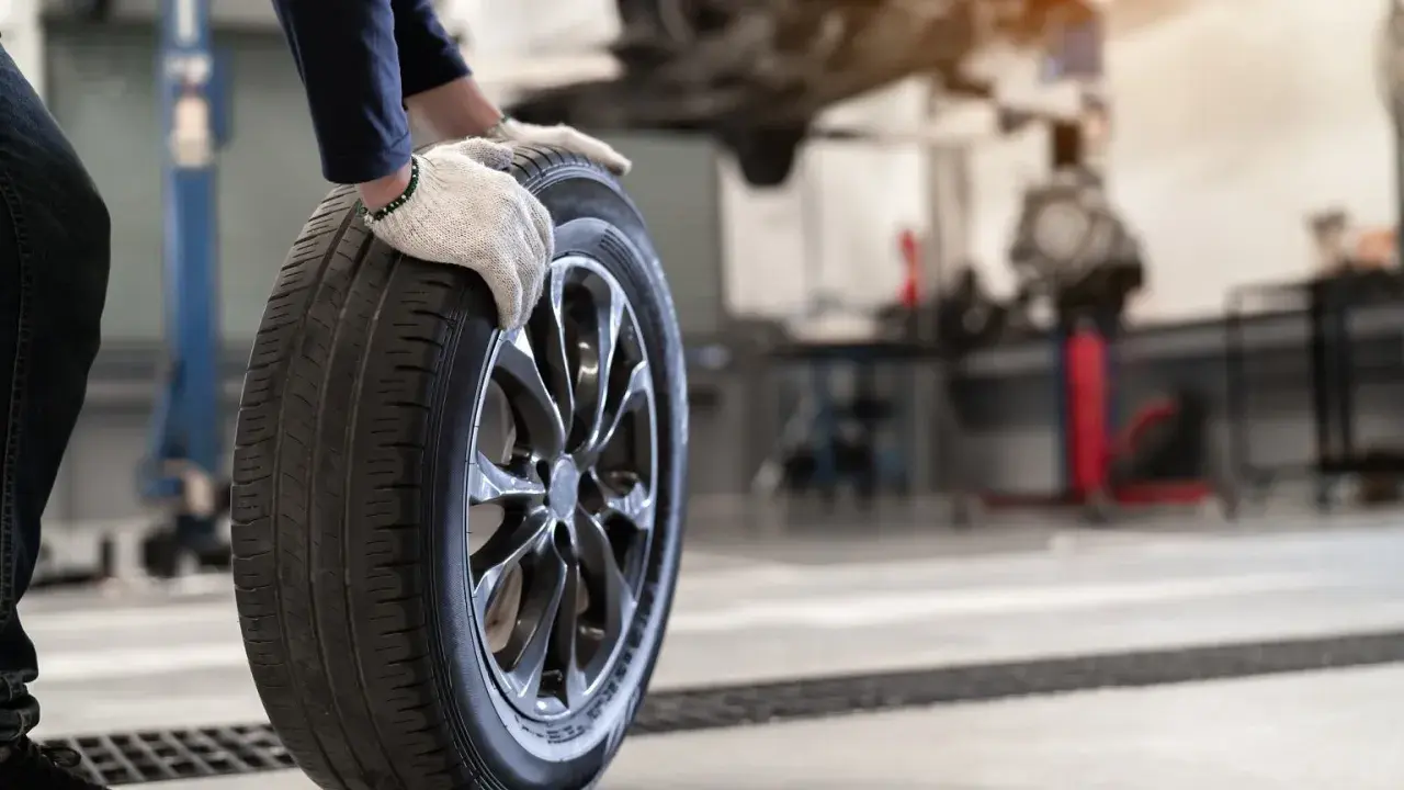 Mechanik w rękawiczkach trzyma oponę. Czy opony rowerowe do miasta z gładkim bieżnikiem zużywają się szybciej na kostce i asfalcie?