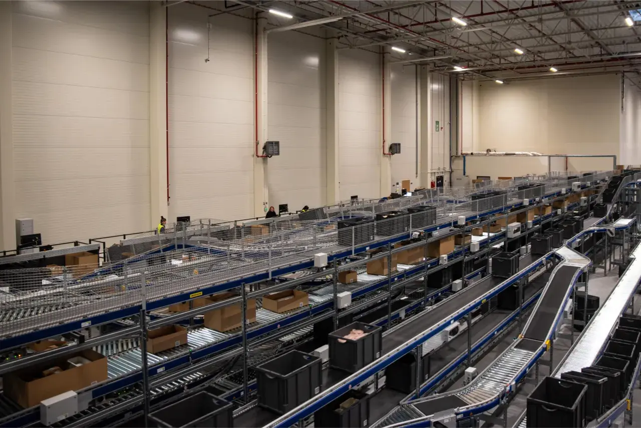 Nowoczesne centrum logistyczne z taśmociągami i pojemnikami, obsługujące usługi e-commerce.