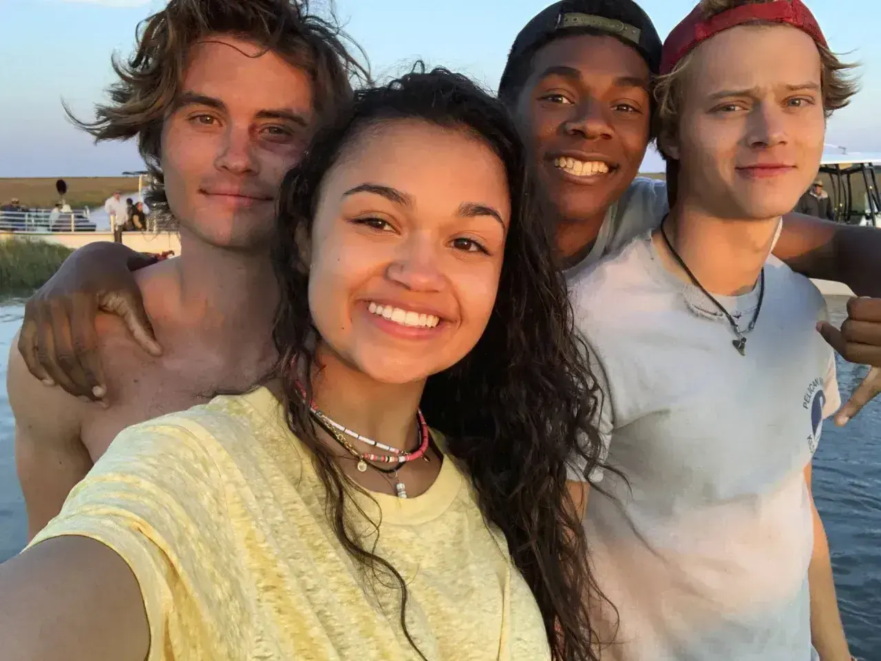 Uśmiechnięta **outer banks obsada** pozuje do selfie na plaży.