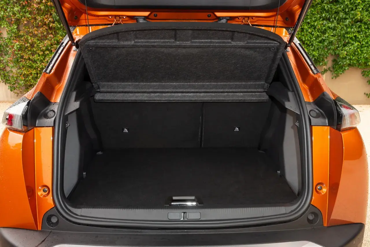 Bagagliaio aperto di una Peugeot 2008 arancione. Le dimensioni sono adatte per un weekend fuori porta.