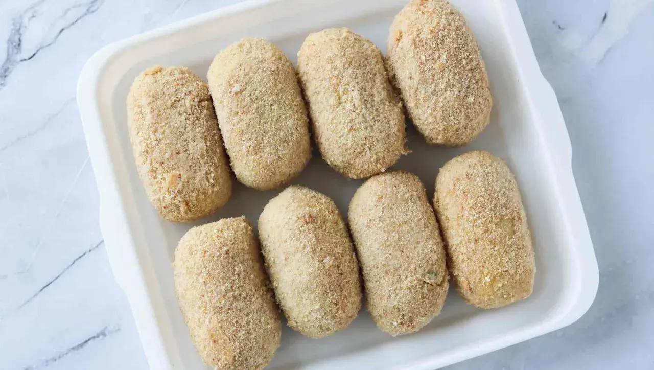 Ocho croquetas empanadas listas para cocinar en la airfryer.