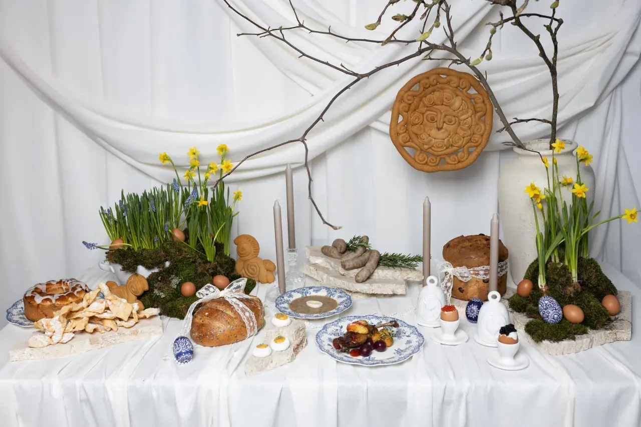 Wielkanocna oferta cateringowa: stół z tradycyjnymi potrawami, babkami, chlebem, jajkami i wiosennymi kwiatami.