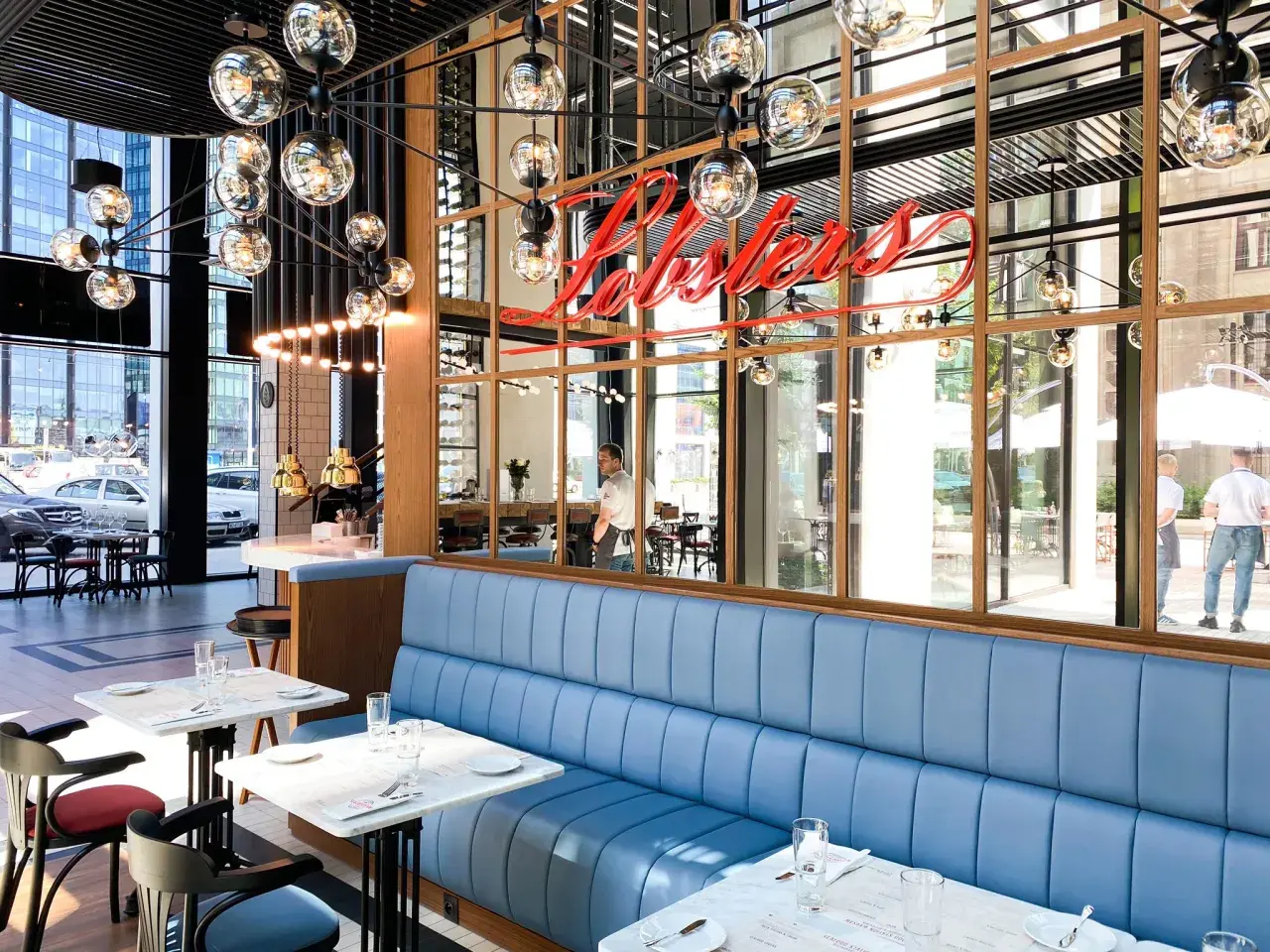 Elegancka restauracja z owocami morza w Warszawie. Neonowy napis "Lobster" nad błękitnymi kanapami.