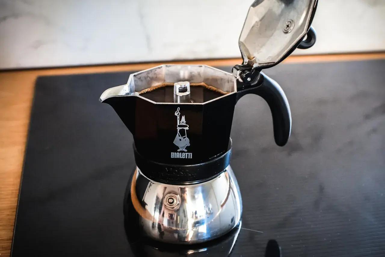 Czarna kawiarka Bialetti z gotową kawą na kuchence. Idealna instrukcja, jak parzyć kawę w kawiarce.