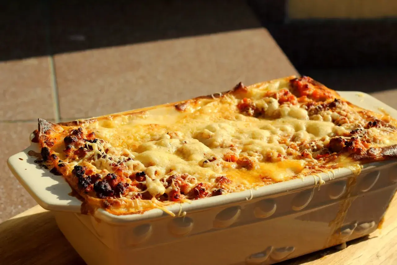 Gorąca, zapieczona lasagne orzepis w naczyniu, z ciągnącym się serem i rumianymi brzegami.