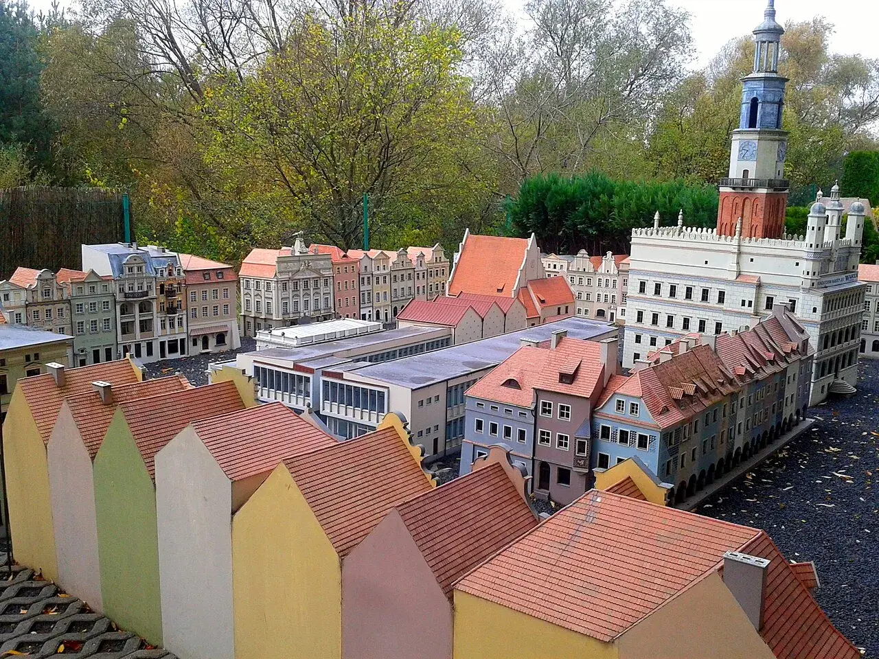 Miniaturowa zabudowa miejska z wieżą zegarową i kolorowymi domkami w skansenie.