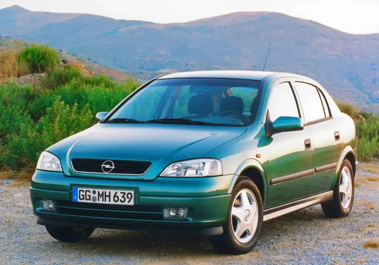 Zielony Opel Astra Classic 1999 na tle górskiego krajobrazu.