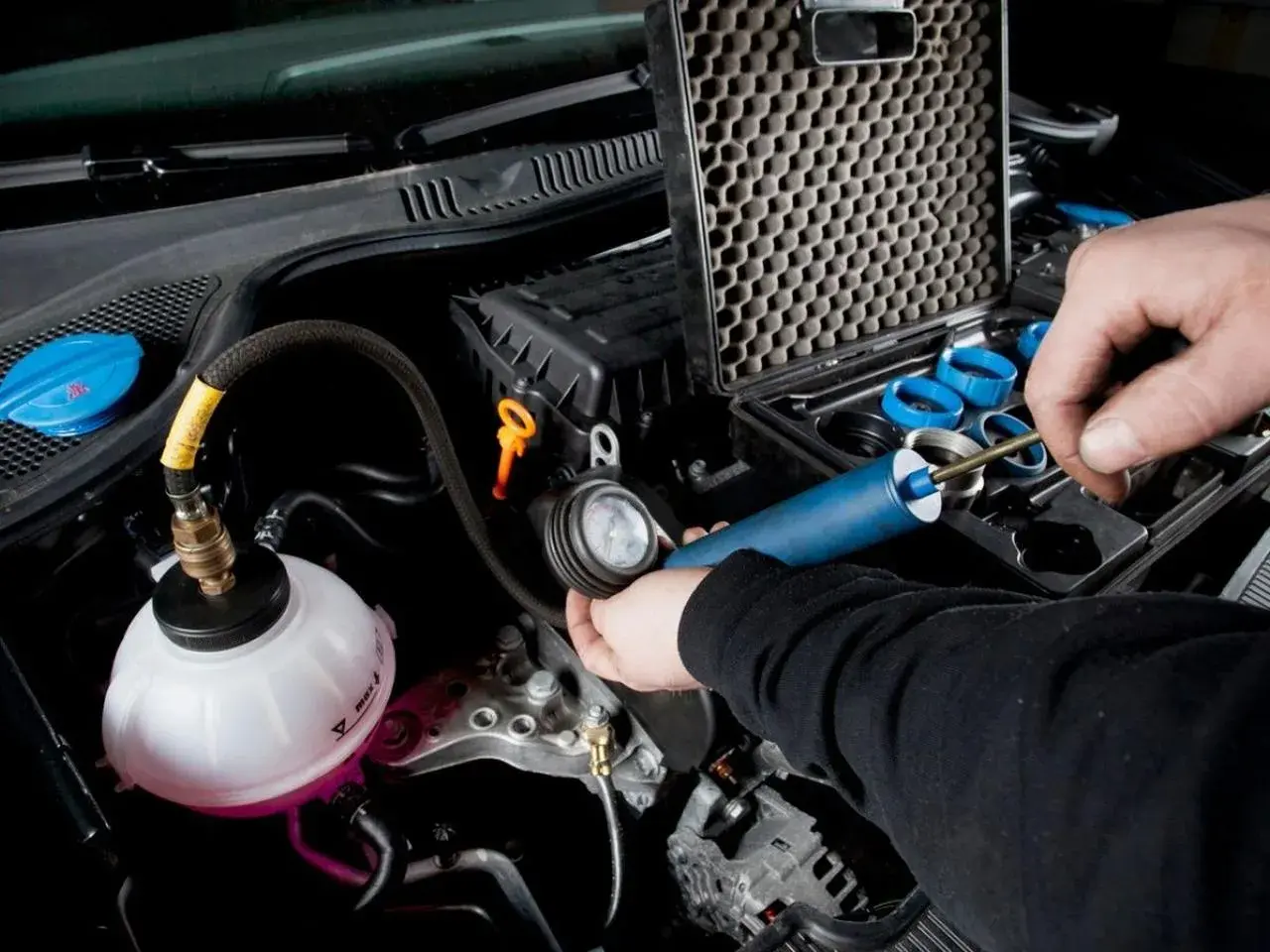 Controllo del radiatore macchina con kit di prova. Un tecnico usa uno strumento per verificare la pressione del sistema di raffreddamento.