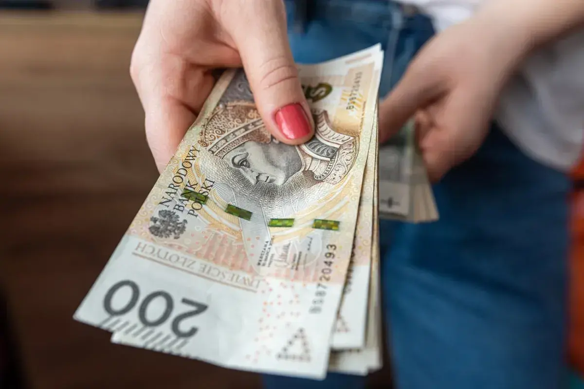 Dłoń trzyma stos banknotów 200 zł. Czekamy na przelew, kiedy ZUS robi przelewy, to zawsze radość!
