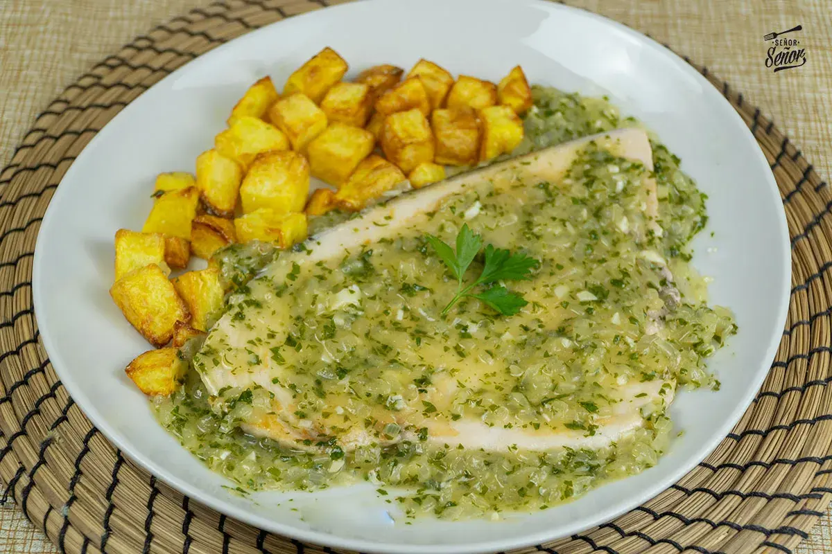 Delicioso emperador a la plancha bañado en salsa verde con patatas fritas crujientes.
