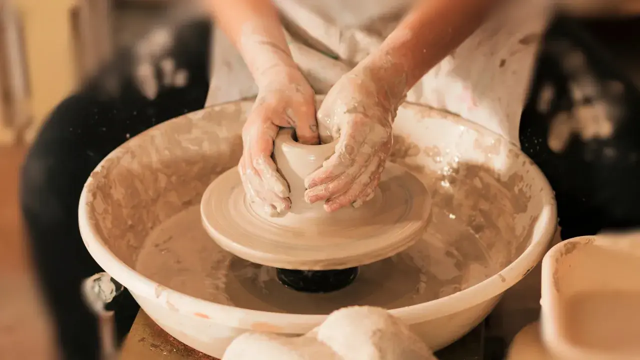 Mani esperte modellano l'argilla su un tornio, creando un pezzo unico di artigianato locale.