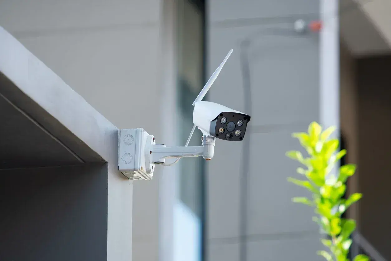 Caméra de surveillance blanche fixée sur un mur extérieur. Une question se pose : peut-on mettre une caméra de surveillance chez soi ?