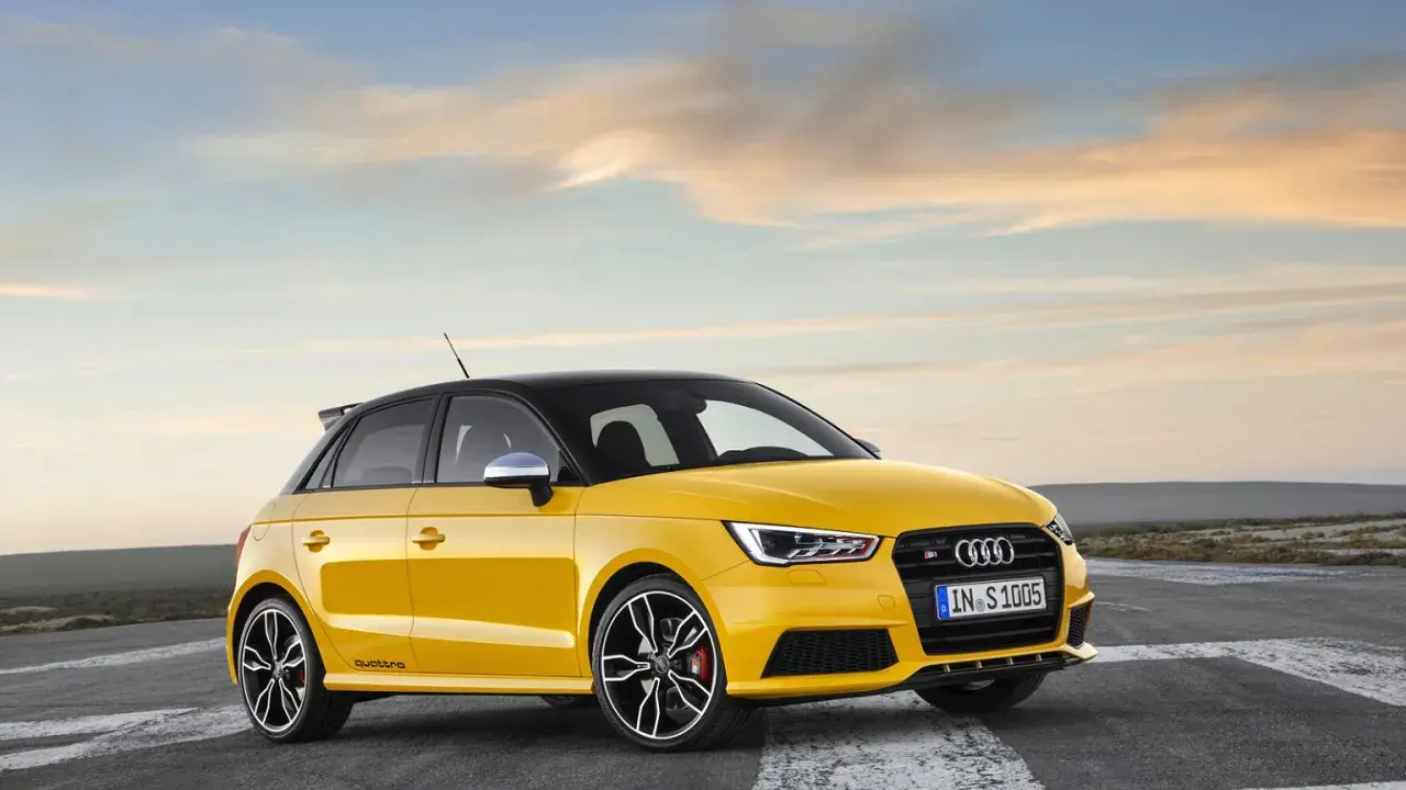 Żółty Audi RS1 z czarnym dachem i felgami, gotowy do jazdy po pustej drodze o zachodzie słońca.